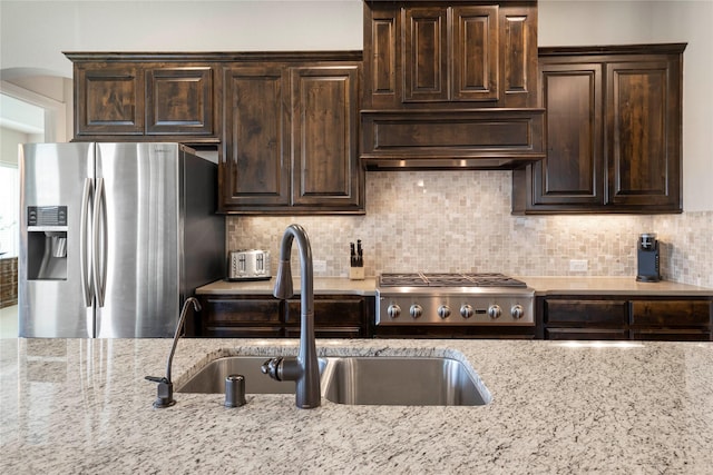 8670 Soto Ln, Frisco, TX 75036 - kitchen featuring appliances with stainless steel finishes, dark brown cabinets, light stone countertops, and a sink