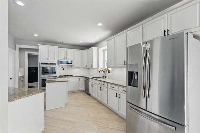 3752 Menard Dr, Carrollton, TX 75010 - kitchen featuring appliances with stainless steel finishes, a center island, recessed lighting, a sink, and light stone countertops
