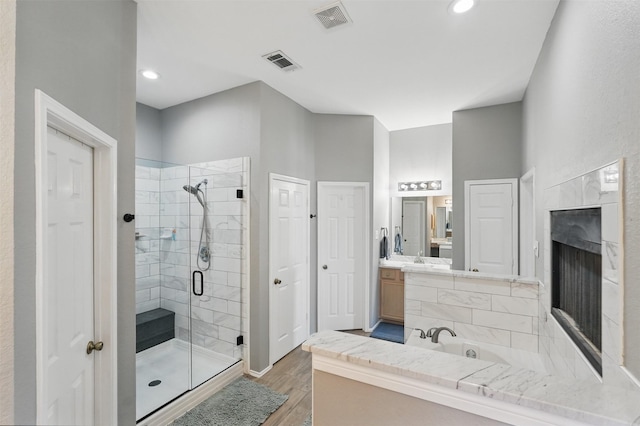 3752 Menard Dr, Carrollton, TX 75010 - full bathroom with a stall shower, vanity, wood finished floors, a tub to relax in, and a fireplace
