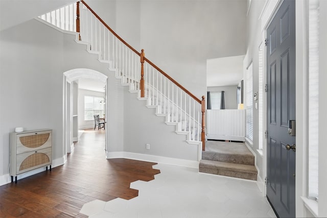 3752 Menard Dr, Carrollton, TX 75010 - foyer entrance featuring a towering ceiling, stairway, arched walkways, wood finished floors, and baseboards