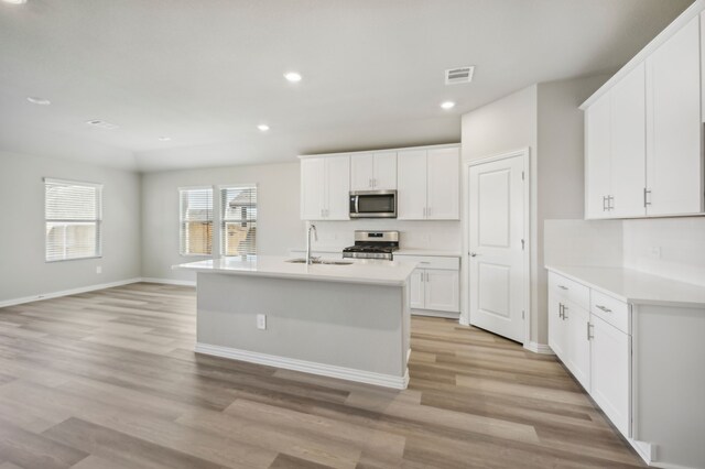 301 Sierra Rdg, Lavon, TX 75166 - kitchen featuring appliances with stainless steel finishes, a sink, light wood finished floors, white cabinets, and recessed lighting
