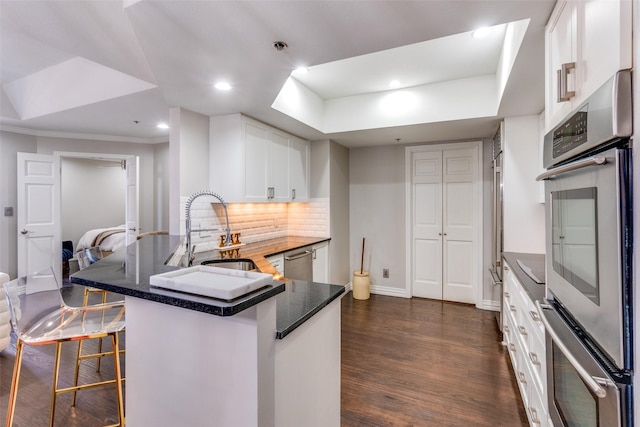 5909 Luther Ln Unit 900, Dallas, TX 75225 - kitchen with a sink, stainless steel appliances, dark wood finished floors, backsplash, and white cabinets