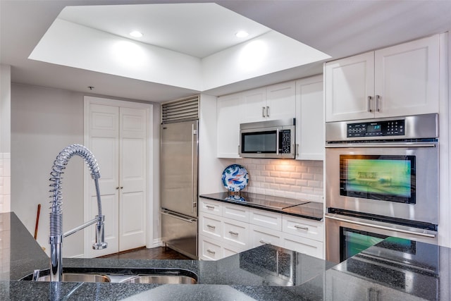 5909 Luther Ln Unit 900, Dallas, TX 75225 - kitchen featuring stainless steel appliances, a sink, white cabinetry, dark stone countertops, and tasteful backsplash