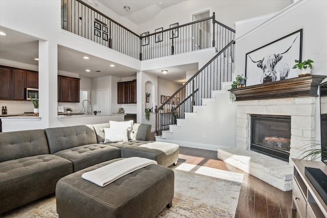 1029 Spring Falls Dr, Mckinney, TX 75071 - living room featuring hardwood / wood-style flooring, a towering ceiling, a stone fireplace, recessed lighting, and baseboards