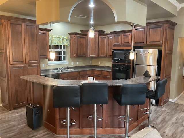 322 Farm Rd Unit 2283, Clarksville, TX 75426 - kitchen featuring black appliances, dark countertops, light wood-style floors, a sink, and a breakfast bar