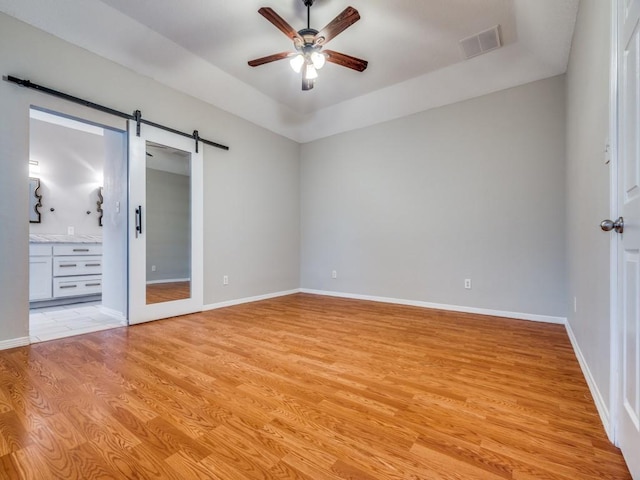 18851 Park Grove Ln, Dallas, TX 75287 - unfurnished bedroom featuring a barn door, light wood finished floors, baseboards, and ensuite bathroom