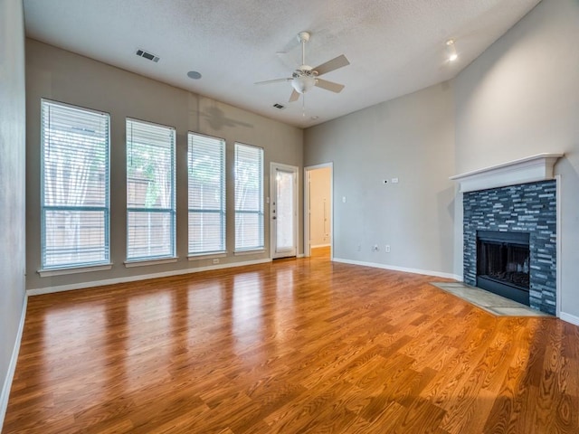 18851 Park Grove Ln, Dallas, TX 75287 - unfurnished living room with a ceiling fan, light wood finished floors, a fireplace, a textured ceiling, and baseboards