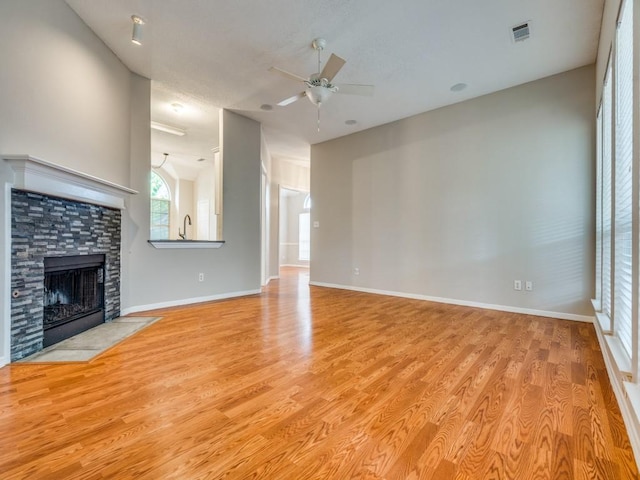 18851 Park Grove Ln, Dallas, TX 75287 - unfurnished living room featuring ceiling fan, light wood-type flooring, a fireplace with flush hearth, and baseboards