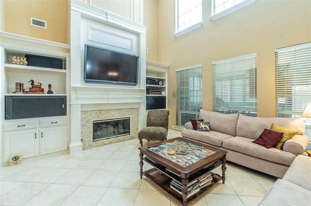 2909 Harkness Dr, Plano, TX 75093 - living room featuring built in features, a towering ceiling, a premium fireplace, and light tile patterned floors