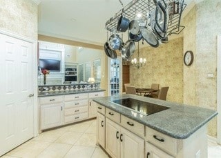 2909 Harkness Dr, Plano, TX 75093 - kitchen with black electric stovetop, dark countertops, a chandelier, light tile patterned floors, and a center island