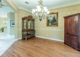 2909 Harkness Dr, Plano, TX 75093 - dining area featuring a chandelier, light wood-style floors, ornamental molding, wallpapered walls, and baseboards