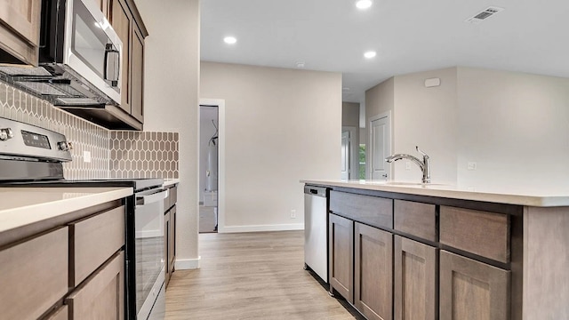 1524 Latimer Ct, Trenton, TX 75490 - kitchen featuring appliances with stainless steel finishes, light wood-style flooring, light countertops, baseboards, and a sink