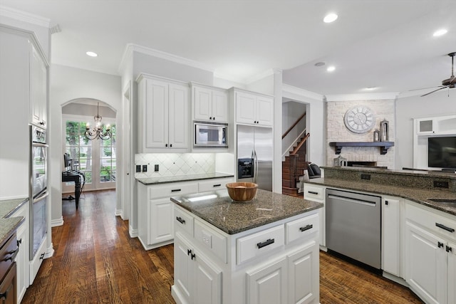 129 Shady Dale Ln, Coppell, TX 75019 - kitchen featuring appliances with stainless steel finishes, arched walkways, backsplash, ceiling fan, and dark wood-type flooring