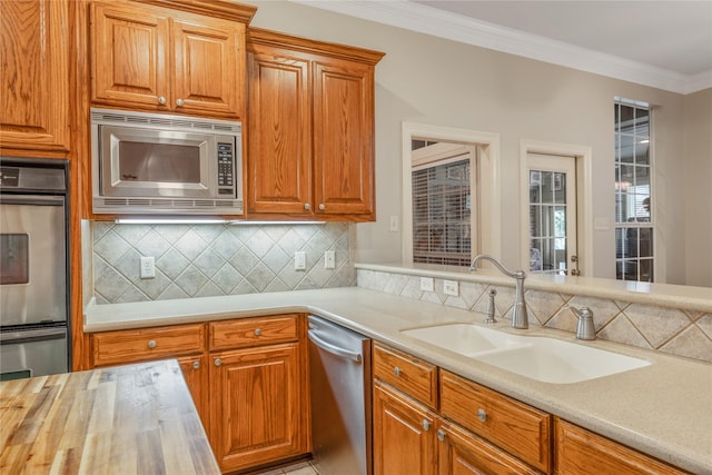 11240 Marsh Wren Cir, Flint, TX 75762 - kitchen featuring stainless steel appliances, decorative backsplash, a sink, crown molding, and brown cabinets