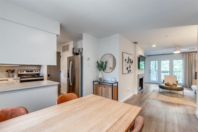 4303 Buena Vista St Unit 206, Dallas, TX 75205 - kitchen featuring appliances with stainless steel finishes, light wood-style flooring, ceiling fan, a fireplace, and light countertops