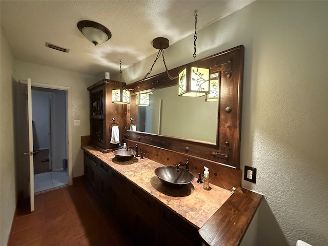 504 Cedar St, Mineral Wells, TX 76067 - full bathroom with a textured wall, backsplash, double vanity, tile patterned flooring, and a textured ceiling