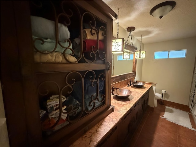 504 Cedar St, Mineral Wells, TX 76067 - bathroom featuring a textured ceiling, toilet, baseboards, double vanity, and tile patterned flooring