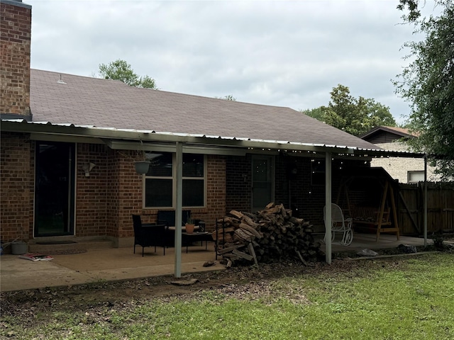 504 Cedar St, Mineral Wells, TX 76067 - back of property with a patio area, brick siding, roof with shingles, and a chimney