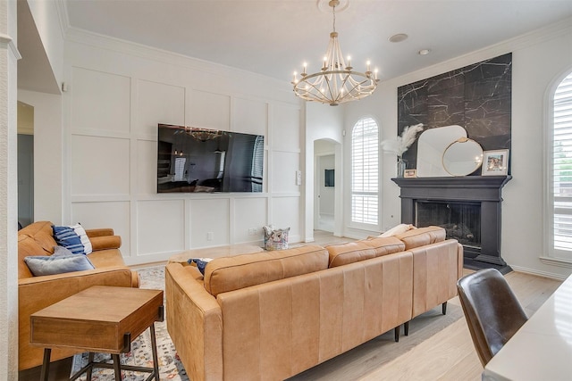 2006 Timber Cove Ct, Weatherford, TX 76087 - living room featuring a chandelier, arched walkways, a large fireplace, light wood finished floors, and crown molding
