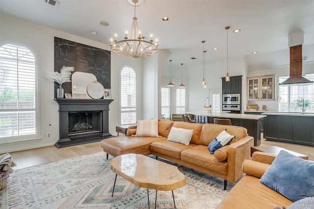 2006 Timber Cove Ct, Weatherford, TX 76087 - living area featuring a chandelier, light wood finished floors, a large fireplace, crown molding, and recessed lighting