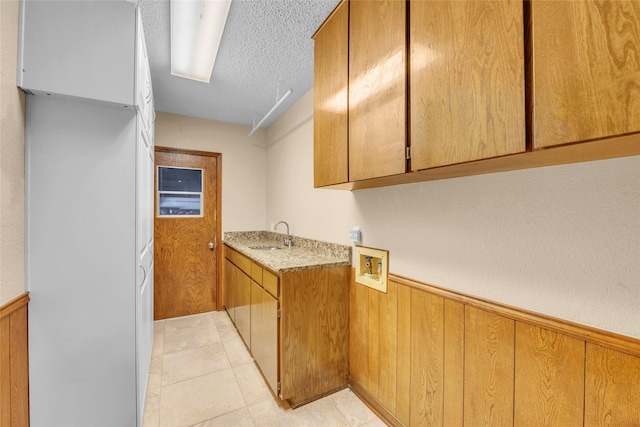 3308 Red Cliff Cir, Temple, TX 76502 - laundry area featuring cabinet space, a wainscoted wall, a textured ceiling, washer hookup, and wooden walls