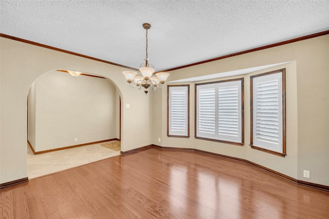3308 Red Cliff Cir, Temple, TX 76502 - unfurnished room with arched walkways, wood finished floors, a textured ceiling, crown molding, and a chandelier