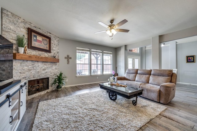 9807 Asheboro St, Frisco, TX 75035 - living room featuring ceiling fan, wood finished floors, a fireplace, baseboards, and a textured ceiling
