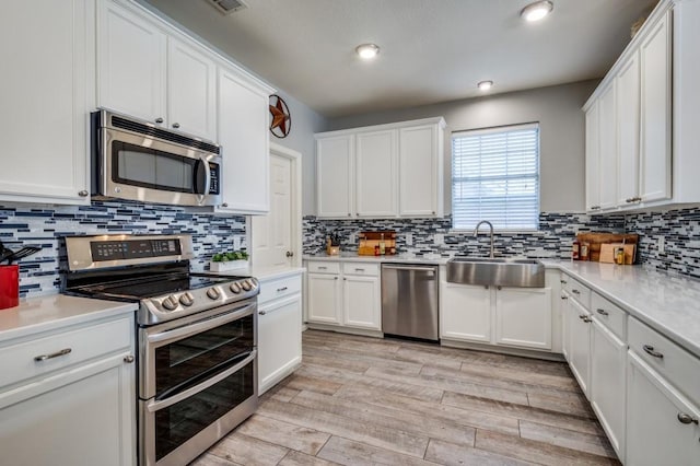 9807 Asheboro St, Frisco, TX 75035 - kitchen featuring stainless steel appliances, a sink, white cabinetry, light wood-style floors, and light countertops