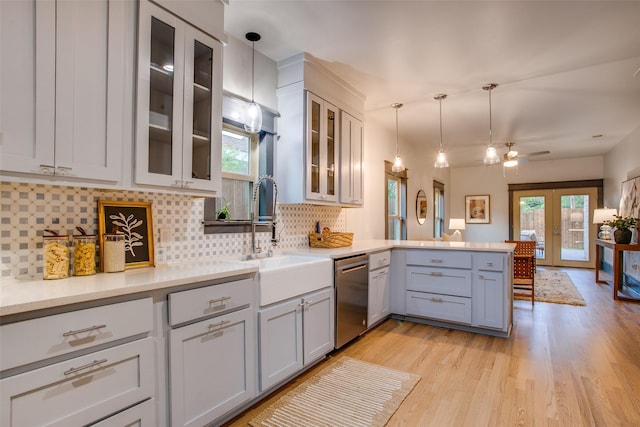 936 N Windomere Ave, Dallas, TX 75208 - kitchen featuring stainless steel dishwasher, a peninsula, decorative backsplash, hanging light fixtures, and light wood finished floors