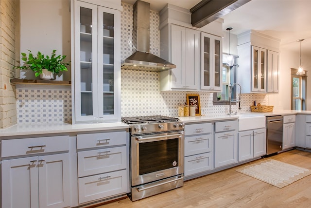 936 N Windomere Ave, Dallas, TX 75208 - kitchen with appliances with stainless steel finishes, wall chimney range hood, tasteful backsplash, and light wood-type flooring