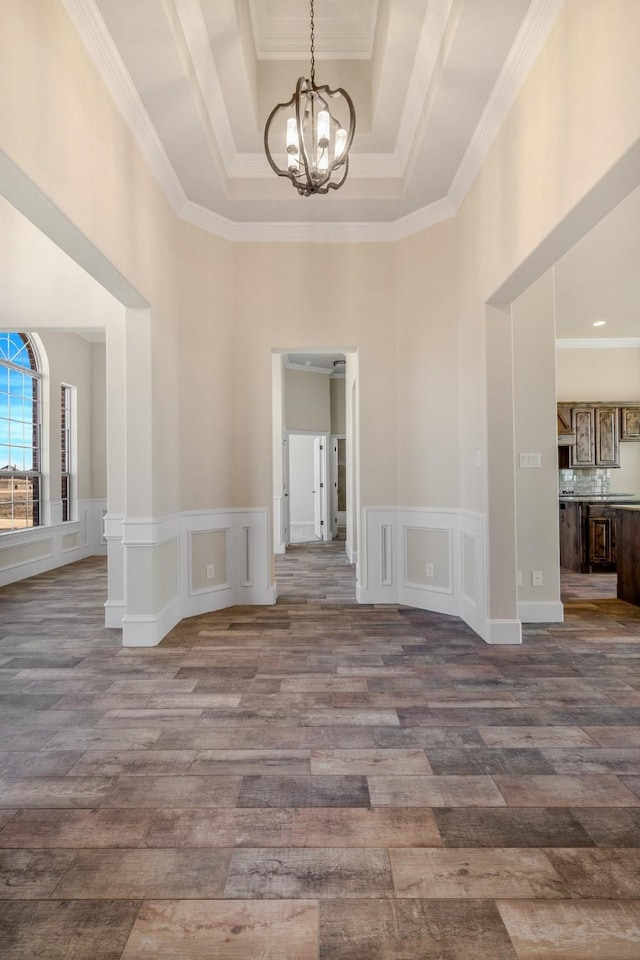 1022 Foolish Pleasure Dr, Terrell, TX 75160 - empty room featuring a chandelier, a high ceiling, a tray ceiling, crown molding, and a decorative wall