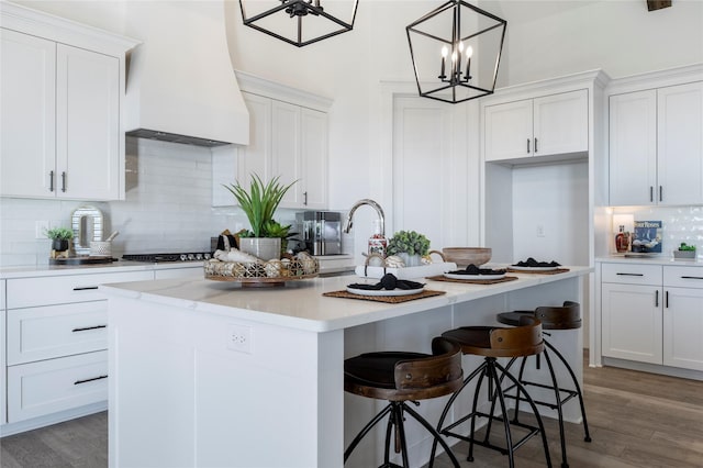4665 Christie Ave, Caddo Mills, TX 75135 - kitchen featuring custom range hood, a kitchen island with sink, decorative backsplash, light wood finished floors, and light countertops