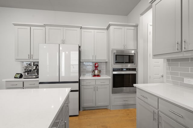 11415 Four Roses Trl, Frisco, TX 75035 - kitchen with stainless steel appliances, backsplash, light countertops, and light wood-style flooring