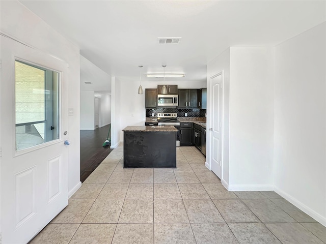 6133 Chalk Hollow Dr, Fort Worth, TX 76179 - kitchen featuring appliances with stainless steel finishes, light tile patterned floors, decorative backsplash, a center island, and baseboards