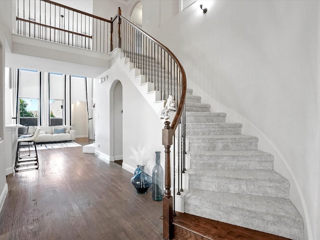 2505 Trailhead Dr, Fort Worth, TX 76177 - staircase featuring arched walkways, a towering ceiling, baseboards, and wood finished floors