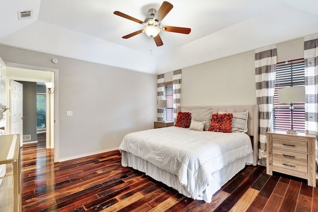 2605 Pickwick Ln, Plano, TX 75093 - bedroom featuring dark wood-style flooring, a tray ceiling, a ceiling fan, baseboards, and multiple windows