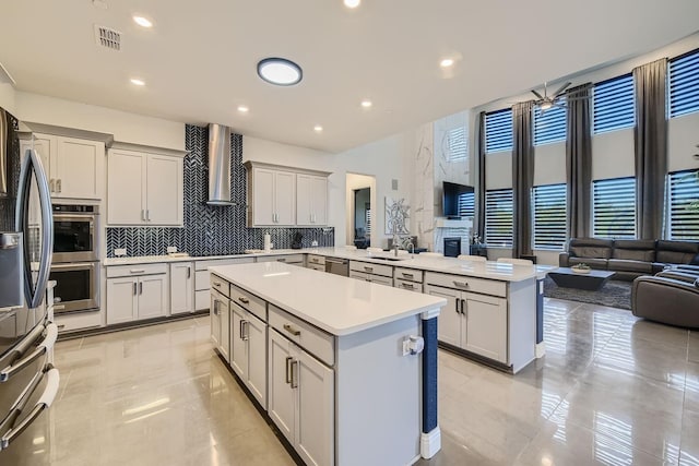 3509 Meridian Dr, Northlake, TX 76226 - kitchen with a peninsula, wall chimney exhaust hood, open floor plan, a kitchen island, and light countertops
