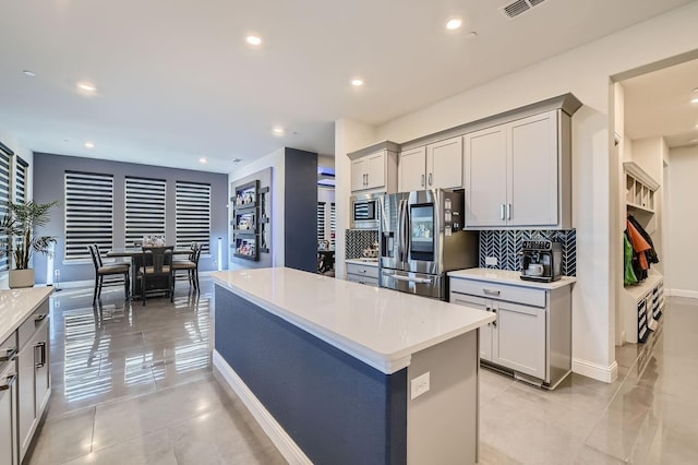 3509 Meridian Dr, Northlake, TX 76226 - kitchen featuring appliances with stainless steel finishes, light countertops, decorative backsplash, a center island, and gray cabinetry