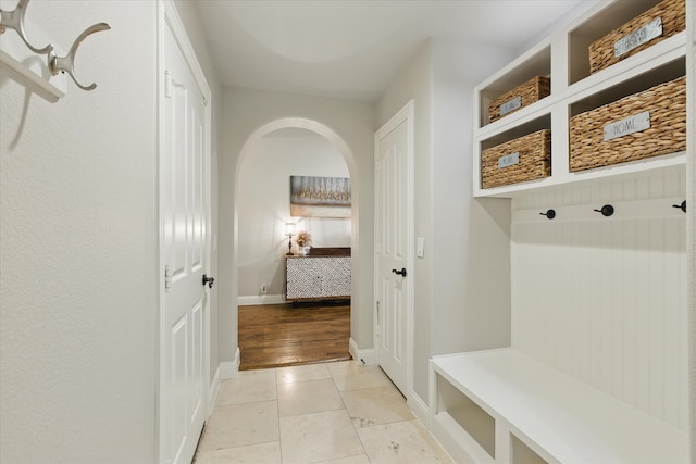 1430 Crescent Valley Dr, Prosper, TX 75078 - mudroom with arched walkways, baseboards, and light tile patterned floors