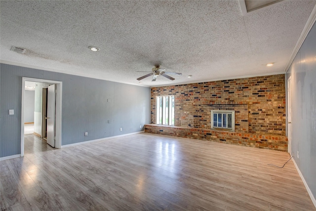 201 Brookhaven Ter, Commerce, TX 75428 - unfurnished living room with a textured ceiling, crown molding, a ceiling fan, wood finished floors, and brick wall