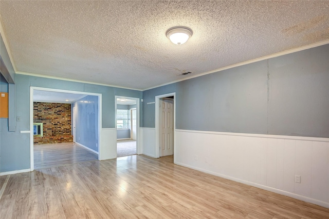 201 Brookhaven Ter, Commerce, TX 75428 - spare room featuring wood finished floors, crown molding, a textured ceiling, and wainscoting
