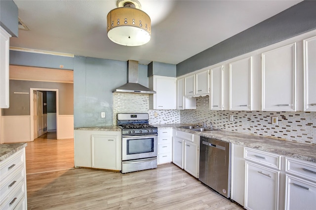 201 Brookhaven Ter, Commerce, TX 75428 - kitchen featuring stainless steel appliances, wall chimney exhaust hood, a sink, light wood-type flooring, and white cabinetry