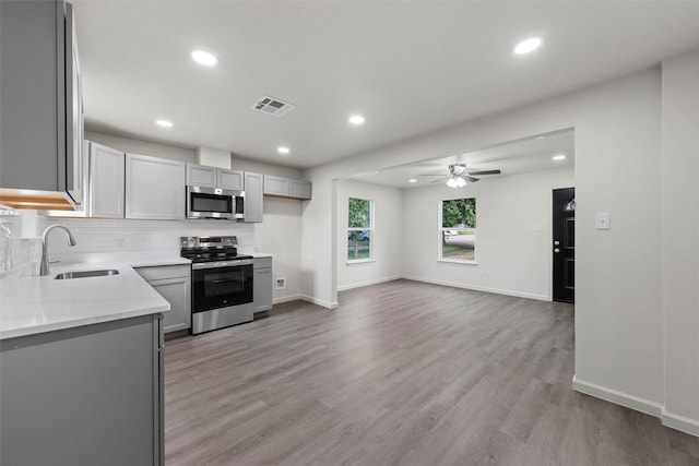 2508 Windsor Ave, Waco, TX 76708 - kitchen with appliances with stainless steel finishes, a sink, a ceiling fan, gray cabinetry, and decorative backsplash
