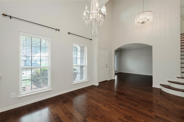 1605 Tanglewood Dr, Allen, TX 75002 - unfurnished dining area with a chandelier, a towering ceiling, arched walkways, wood-type flooring, and stairs