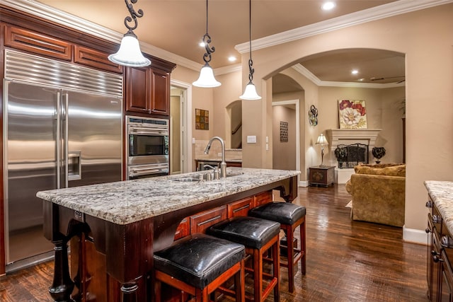 11626 Coronado Trl, Frisco, TX 75033 - kitchen featuring stainless steel appliances, arched walkways, a sink, baseboards, and light stone countertops