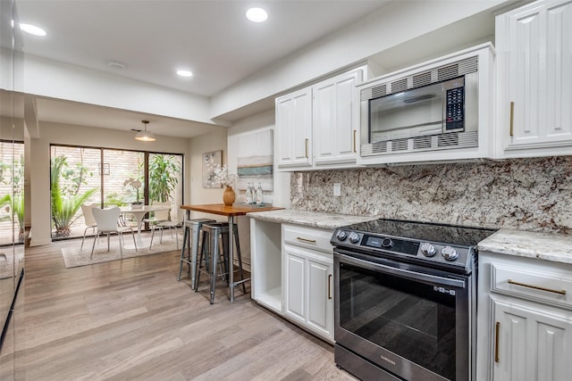 9502 Summerhill Ln, Dallas, TX 75238 - kitchen featuring appliances with stainless steel finishes, light wood-style floors, white cabinetry, recessed lighting, and decorative backsplash