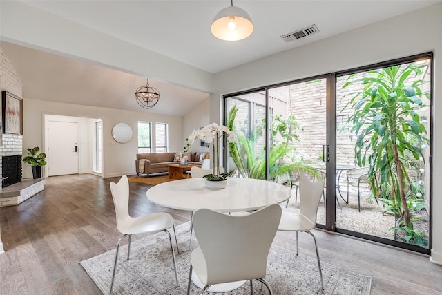 9502 Summerhill Ln, Dallas, TX 75238 - dining space with baseboards, light wood-type flooring, a brick fireplace, a chandelier, and lofted ceiling