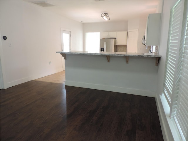 622 N Race, Stephenville, TX 76401 - kitchen featuring stainless steel refrigerator with ice dispenser, a peninsula, a breakfast bar area, light stone countertops, and wood finished floors
