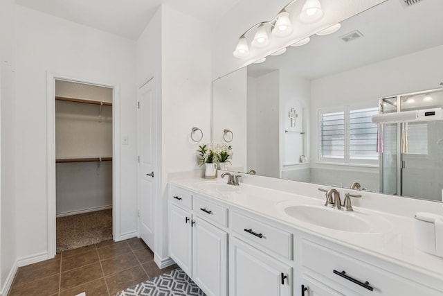 5016 Coney Island Dr, Frisco, TX 75036 - bathroom featuring double vanity, a stall shower, tile patterned floors, a walk in closet, and baseboards