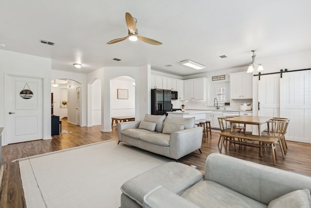 5016 Coney Island Dr, Frisco, TX 75036 - living room with arched walkways, wood finished floors, a ceiling fan, and a barn door